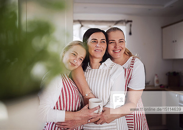 Mutter und Töchter stehen in der Küche und umarmen
