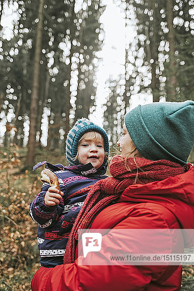Mutter trägt kleine Tochter im Herbstwald