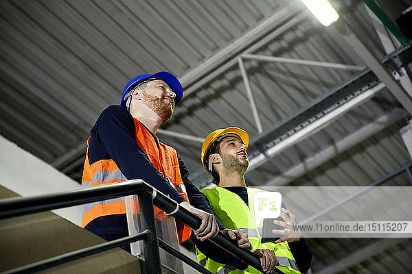 Two workers standing on upper floor in factory