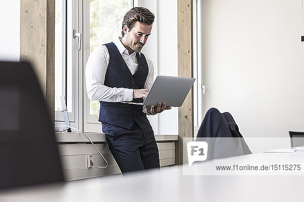 Businessman standing at the window  using laptop