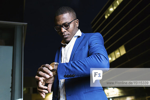 Junger Geschäftsmann trägt blaue Anzugsjacke und überprüft die Uhrzeit