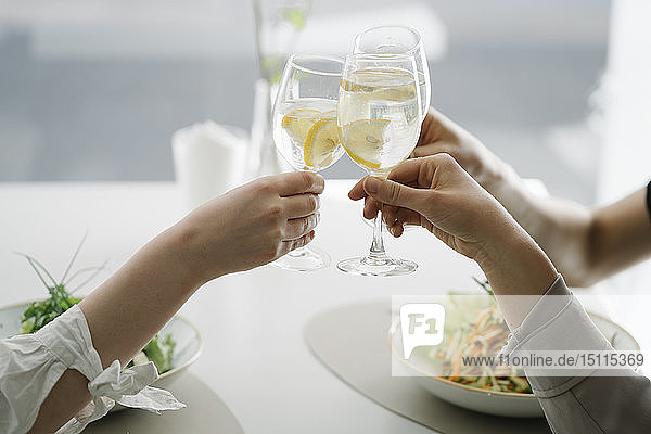 Nahaufnahme von drei Frauen  die in einem Restaurant auf ein Glas Wasser anstoßen