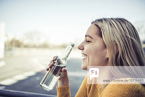 Profil einer lachenden jungen Frau mit Erfrischungsgetränk