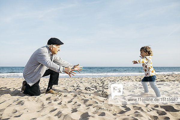 Großvater spielt mit seiner Enkelin am Strand