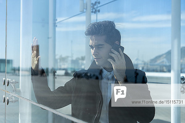 Businessman on the phone in the city behind glass pane
