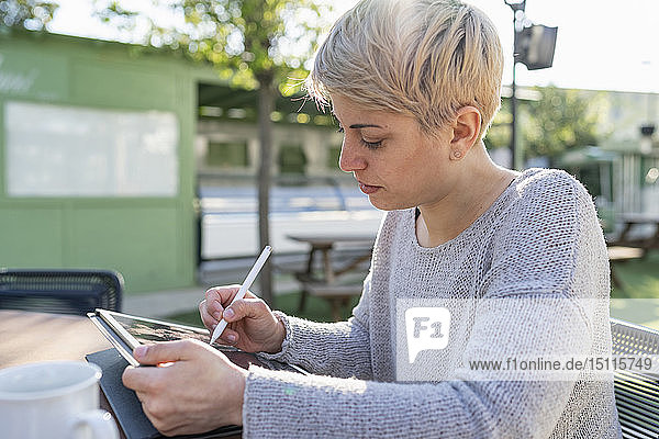 Junge Frau benutzt digitales Tablett im Freien