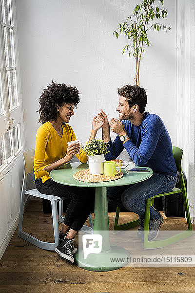 Glückliches  liebevolles Paar sitzt zu Hause am Tisch