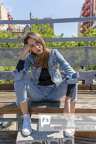 Junge Frau sitzt auf einer Bank in Barcelona