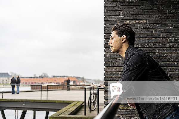 Dänemark  Kopenhagen  junger Mann lehnt am Wasser an einem Geländer