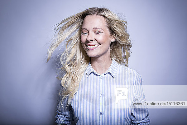 Porträt einer glücklichen blonden Frau  die ihr Haar wirft