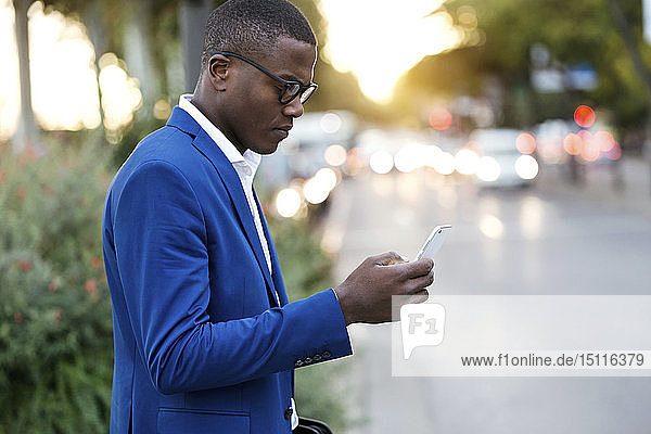 Young businessman wearing blue suit jacket and using smartphone