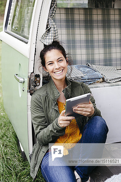 Junge Frau mit digitalem Tablett  in ihrem Wohnwagen sitzend