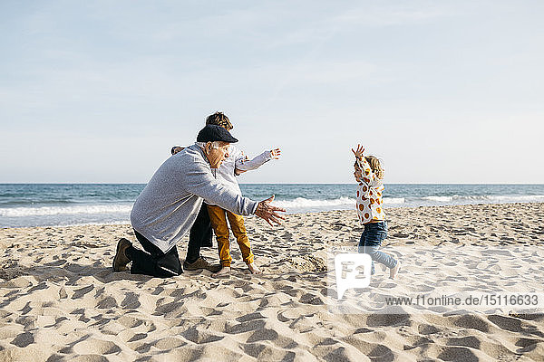 Grandfather playing with his grandchildren on the beach in spring