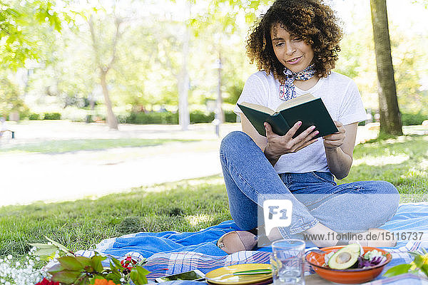 Relaxed woman with book having a picnic in park