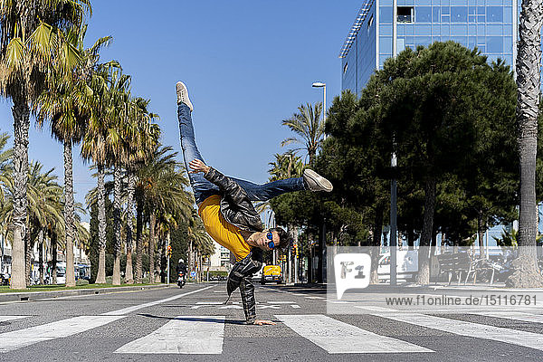 Spain  Barcelona  man in the city doing a handstand on the street
