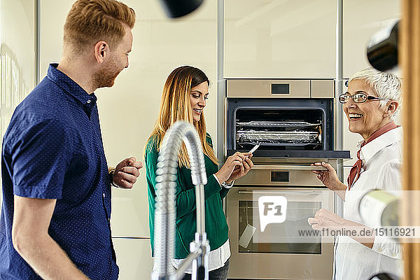 Shop assistant explaining oven to couple shopping for a new kitchen in showroom