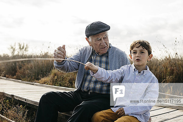 Großvater und Enkel sitzen mit auf der Strandpromenade und entspannen