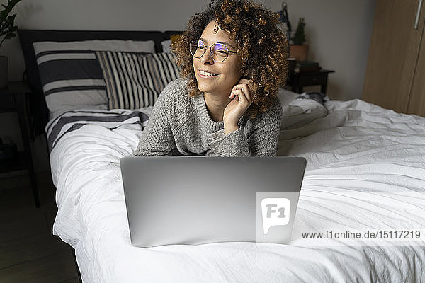 Woman lying on bed  using laptop  surfing the net
