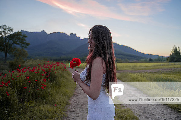Elegante junge Frau hält auf dem Land eine Mohnblume in der Hand  Garrotxa  Spanien