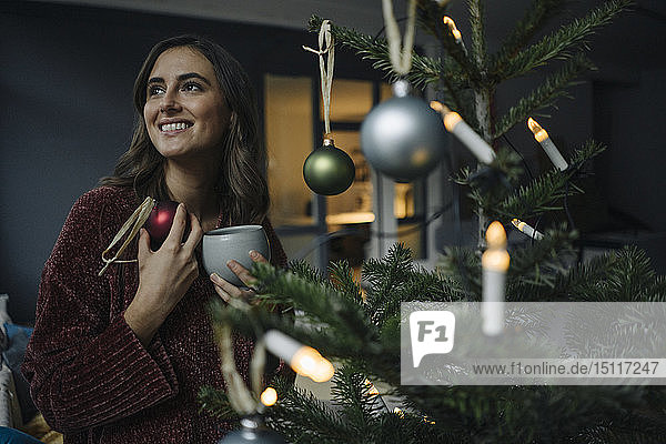 Smiling young woman decorating Christmas tree