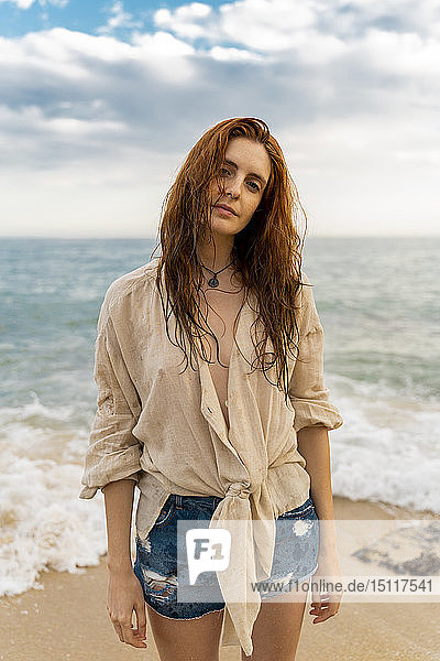 Porträt einer rothaarigen jungen Frau mit Nasenpiercing am Strand stehend