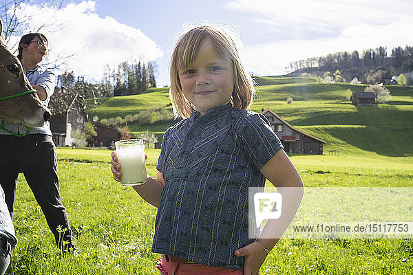 Porträt eines lächelnden Mädchens mit einem Glas frischer Milch auf der Weide