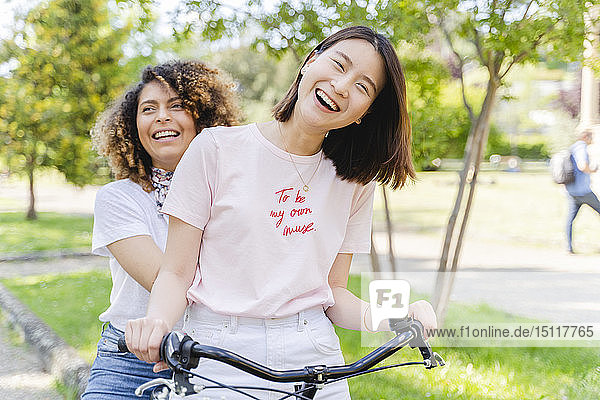 Zwei glückliche Frauen auf dem Fahrrad im Park
