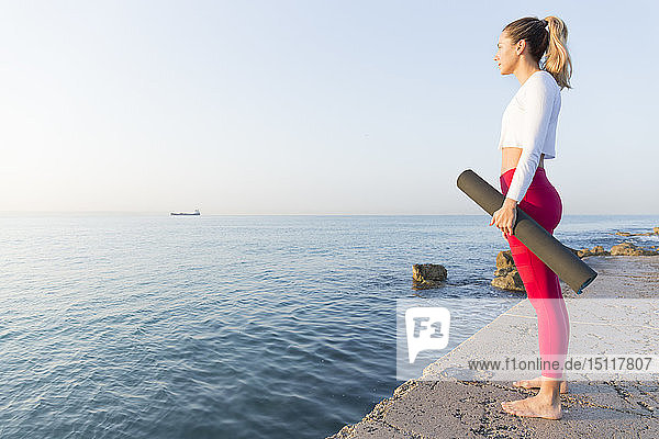 Junge Frau praktiziert Yoga am Strand