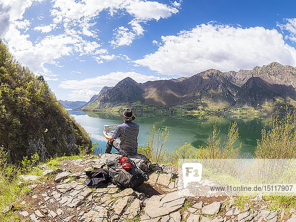 Italy  Lombardy  spring at Lake Idro  hiker sitting with map at observation point