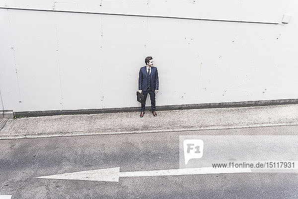 Businessman standing at road with arrow sign
