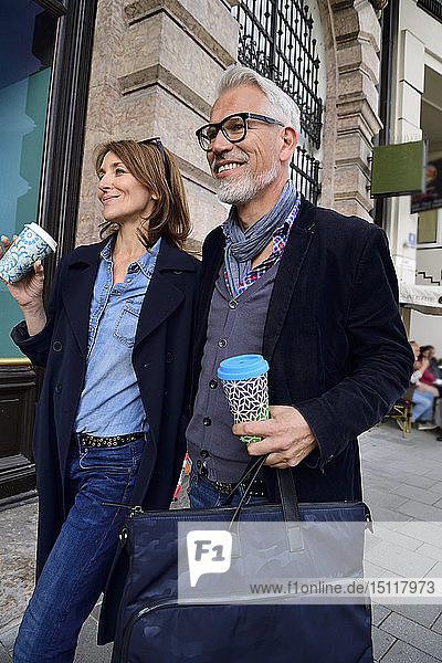 Smiling mature couple with reusable bamboo cups walking in the city