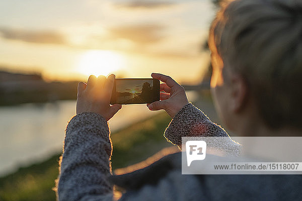 Rückenansicht der Frau  die den Sonnenuntergang fotografiert  Nahaufnahme