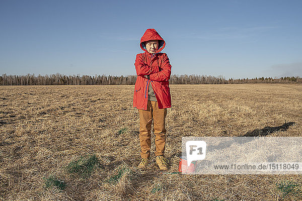 Serious boy with paint bucket in steppe landscape