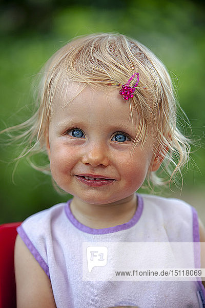 Bildnis eines blonden kleinen Mädchens mit Lätzchen und rosa Haipin