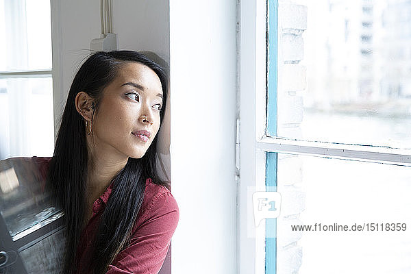 Portrait of woman looking out of window in office
