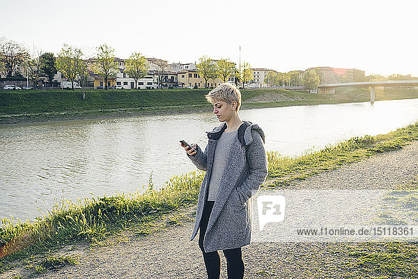 Junge Frau benutzt Mobiltelefon im Freien