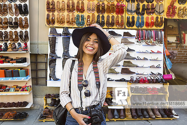 Italy Florence portrait of happy young tourist with camera and backpack on street market