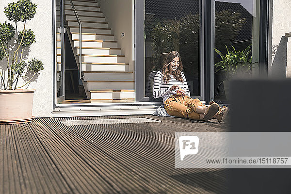 Junge Frau sitzt zu Hause auf der Terrasse
