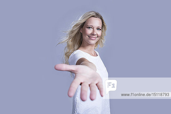 Porträt einer lächelnden blonden Frau  die ihre helfende Hand anbietet