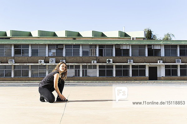 Portrait of teenage girl crouching outdoors