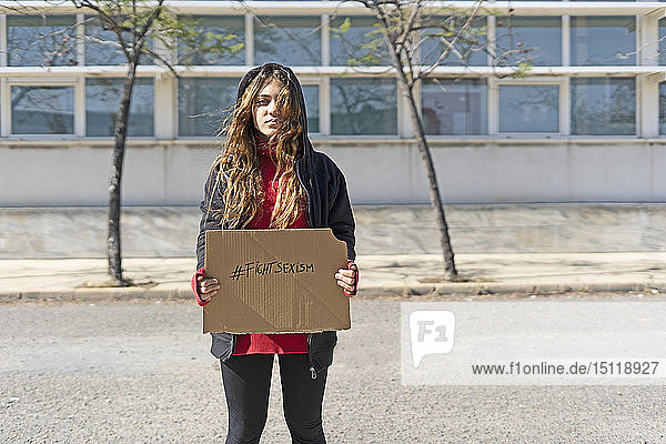 Porträt einer ernsthaften Teenagerin  die den Hashtag gegen Sexismus auf Pappe zeigt
