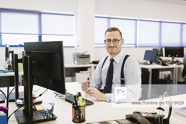 Porträt eines selbstbewussten Geschäftsmannes am Schreibtisch im Büro