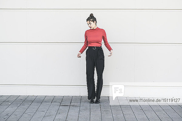 Elegante junge Frau die an einer Wand steht