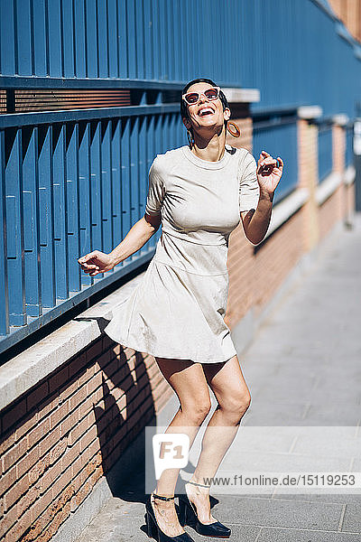 Happy fashionable young woman wearing dress and sunglasses