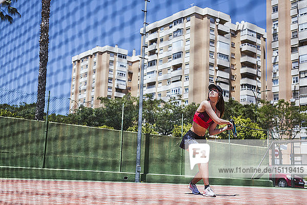 Tennisspielerin  die auf einem Platz in der Stadt spielt