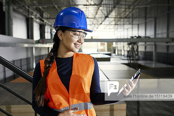 Smiling female worker using tablet in factory warehouse