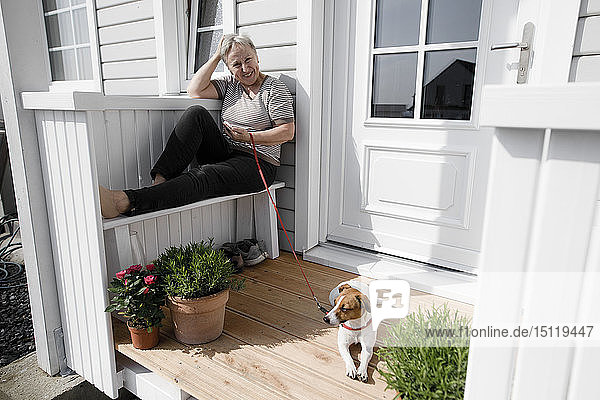 Relaxed senior woman sitting on porch with her dog