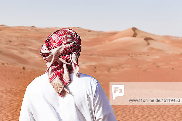 Bedouin in National dress standing in the desert  rear view  Wahiba Sands  Oman