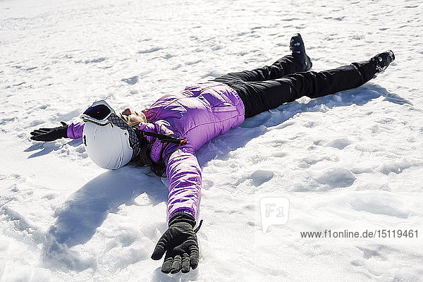 Woman taking a break after skiing lying on the snowy ground in Sierra Nevada  Andalusia  Spain