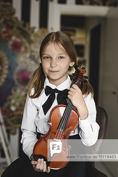 Portrait of a smiling girl with a violin at home